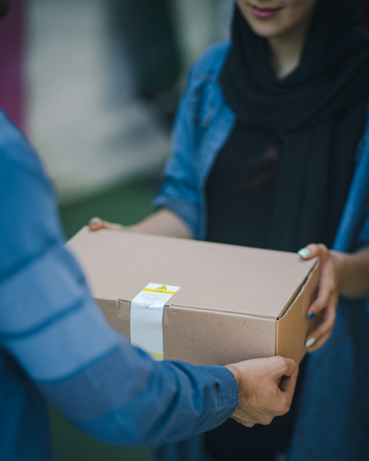 Two people passing a sealed brown cardboard parcel between them
